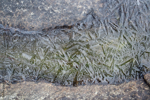 Ice pattern on the rocky lake shore ice