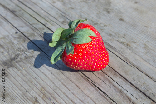 Single strawberry on sunny wooden background