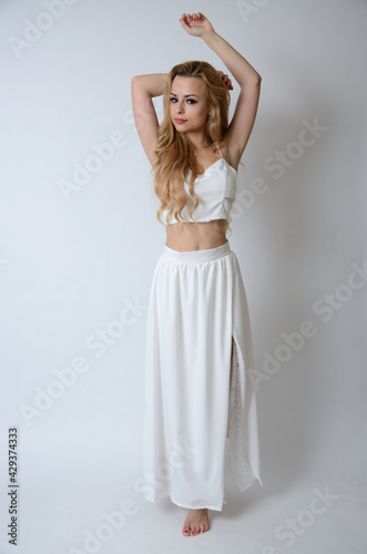 Polish model posing with white top, long white dress with cut, showing her legs. © BartekMagierowski