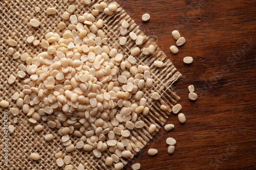 Macro Close-up of Organic split and polished White Urad Dal  Vigna mungo  on Jute mat and wooden top.