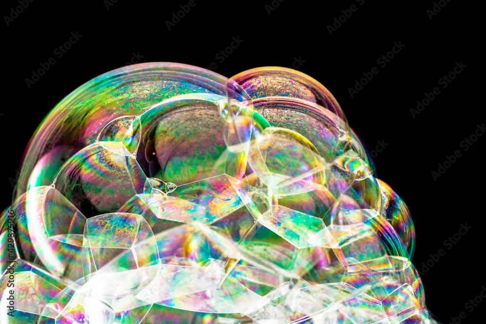 Macro photo of iridescent soap bubbles stacked creating a rainbow-coloured foam 