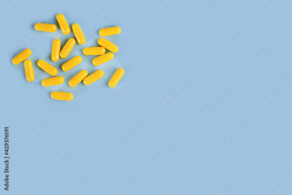 Yellow pills on the blue background. Healthcare and medicine. Place for text. Close-up.