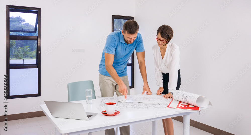 Obraz premium A female realtor and a man looking plan and drawing new house and discussing