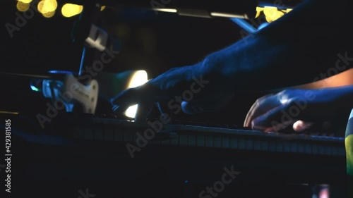 A keyboard player plays a synthesizer in the spotlight. Low key