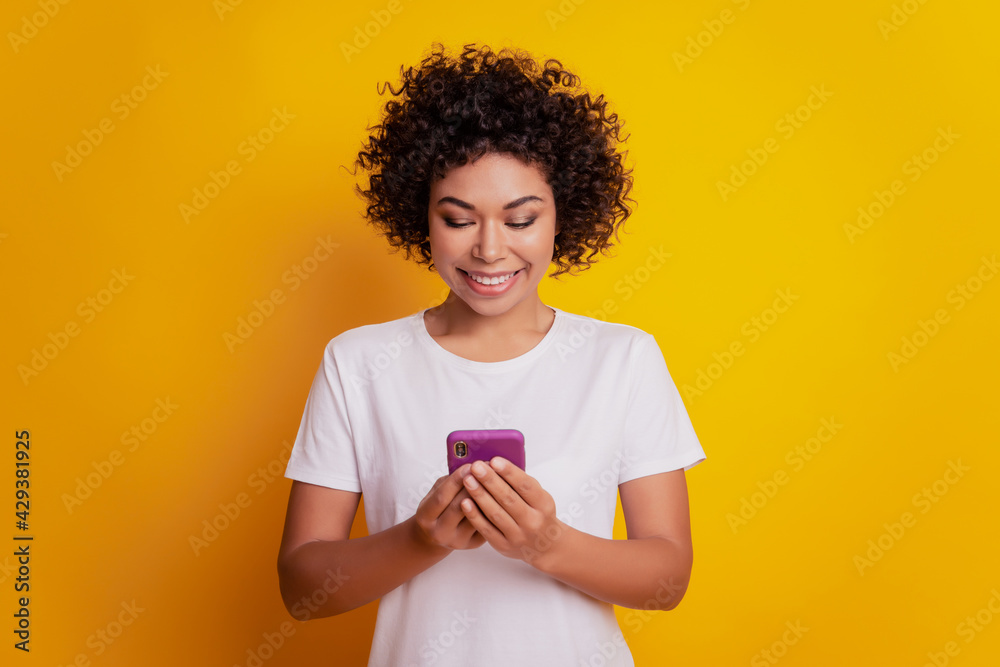 Content trendy cheerful nice cute adorable girl hold phone texting on yellow background Content trendy cheerful nice cute adorable girl hold phone texting on yellow background