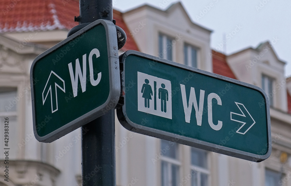WC sign, logo of public toilets in the street against building background. For female, male. Public toilet sign against building. WC sign, logo of public toilets in the street against building background. For female, male. Public toilet sign against building.