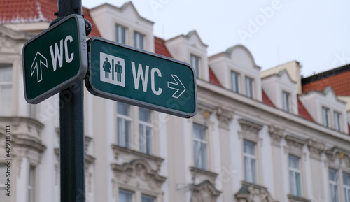 WC sign, logo of public toilets in the street against building background. For female, male. Public toilet sign against building. © Yuliya