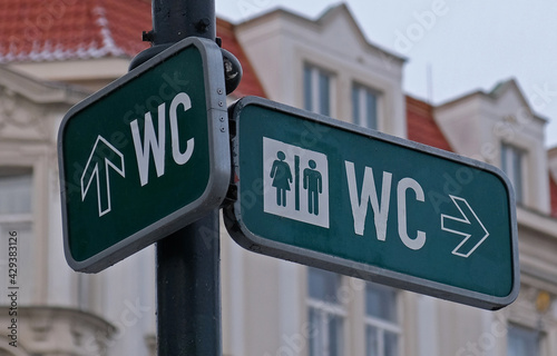 WC sign, logo of public toilets in the street against building background. For female, male. Public toilet sign against building.  © Yuliya
