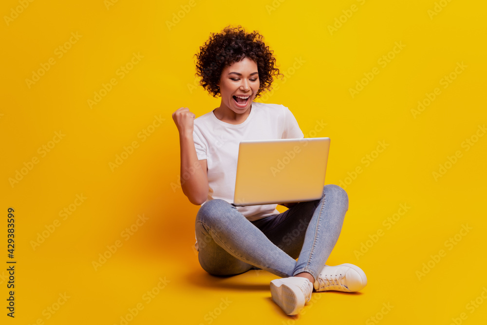 Smiling woman typing on laptop computer raise fist scream open mouth on yellow background Smiling woman typing on laptop computer raise fist scream open mouth on yellow background