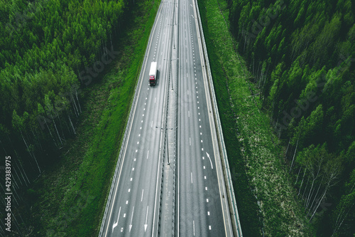 Aerial view of toll road highway with cars and trucks through green forest