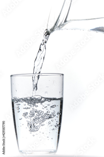 Glass of water being filled. Close up pouring clear water in transparent drinking glass over white background