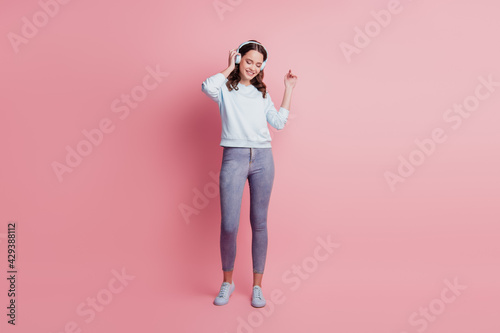 Young woman wear headphones listening music carefree mood on pink background