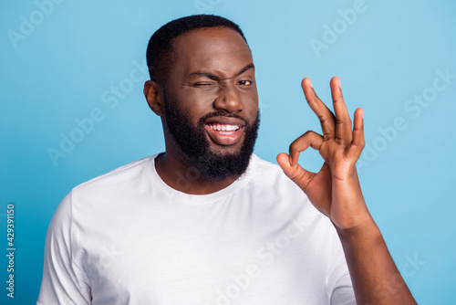 Fényképezés Photo of african businessman show okey sign blink eye on blue background