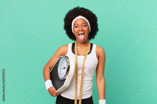 afro woman with cheerful, carefree, rebellious attitude, joking and sticking tongue out, having fun diet concept photo