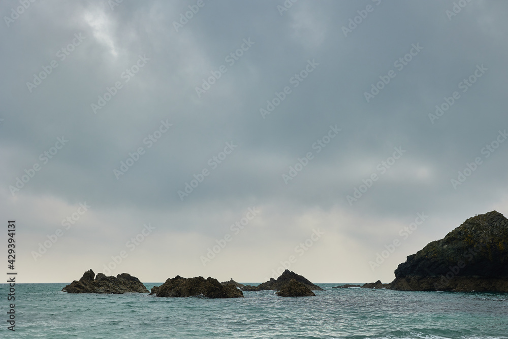 rocks in Atlantic ocean surrounded by water and with cloudy sky.