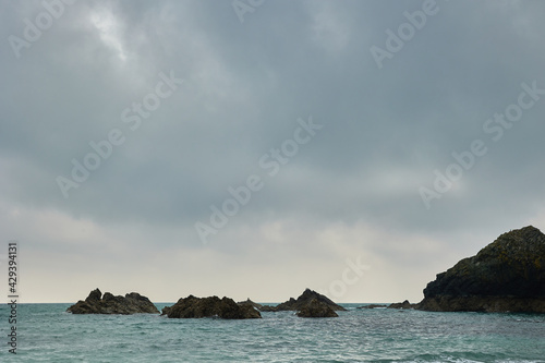rocks in Atlantic ocean surrounded by water and with cloudy sky.
