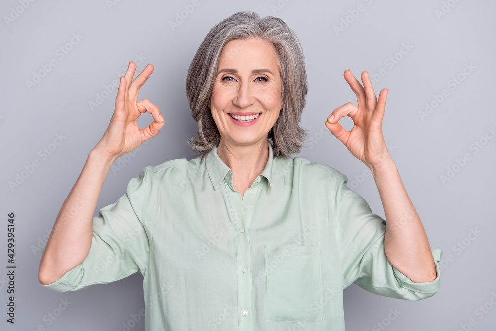 Photo of happy smiling beautiful lovely woman showing okay sign agreement isolated on grey color background Photo of happy smiling beautiful lovely woman showing okay sign agreement isolated on grey color background