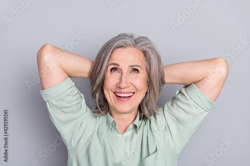 Photo of happy cheerful dreamy smiling mature woman look up copyspace relaxing isolated on grey color background