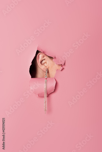 Cropped view of woman in earring near pink background with hole Fototapet