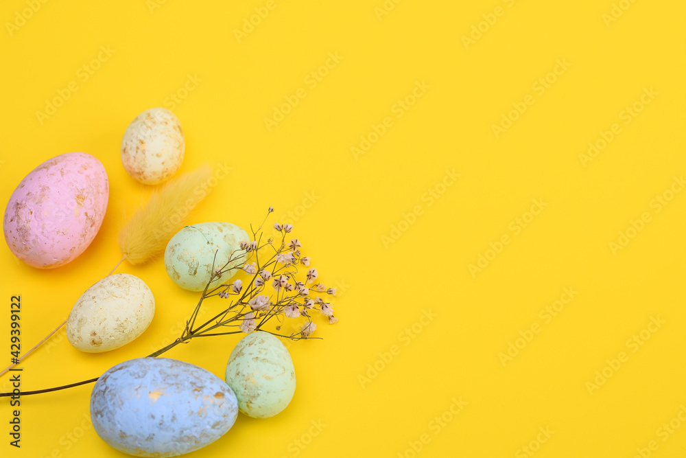 Easter eggs, a sprig of gypsophila, a lagurus on a yellow background. copy space