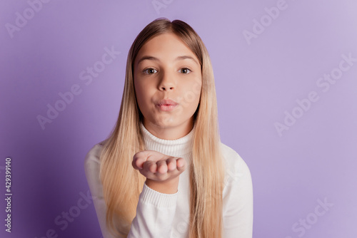 Photo of dreamy affectionate lady send air kiss wear white jumper posing on purple background