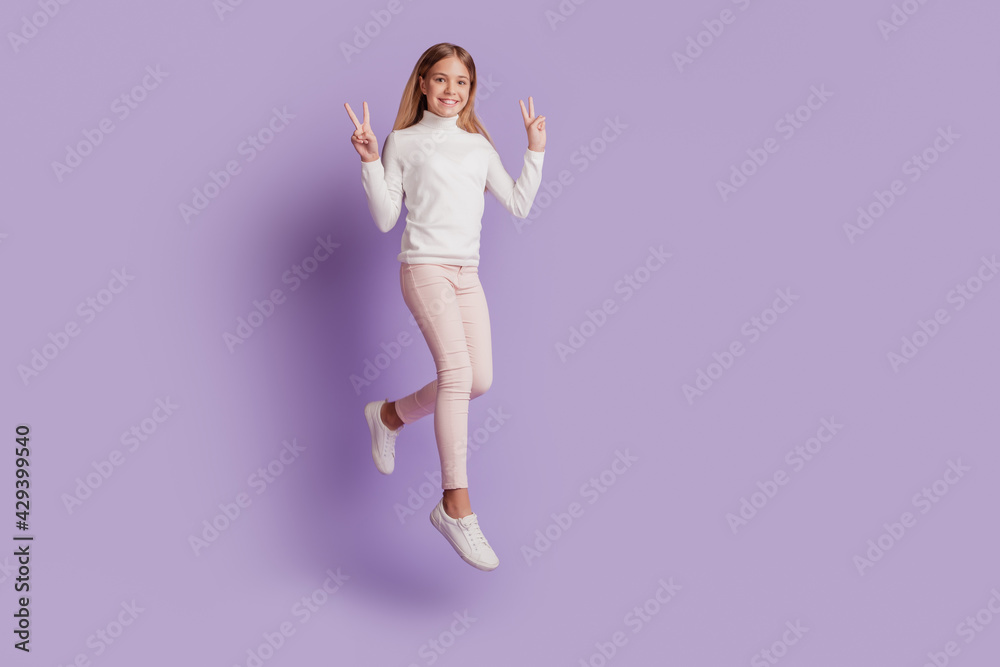 Photo of crazy astonished lady jump raise fists wear white jumper posing on purple background Photo of crazy astonished lady jump raise fists wear white jumper posing on purple background