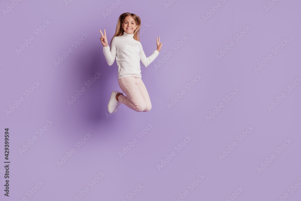 Photo of positive adorable lady jump raise fists celebrate victory wear white jumper posing on purple background