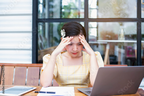 Young woman sitting in a cafe with her laptop, Stressful for work.