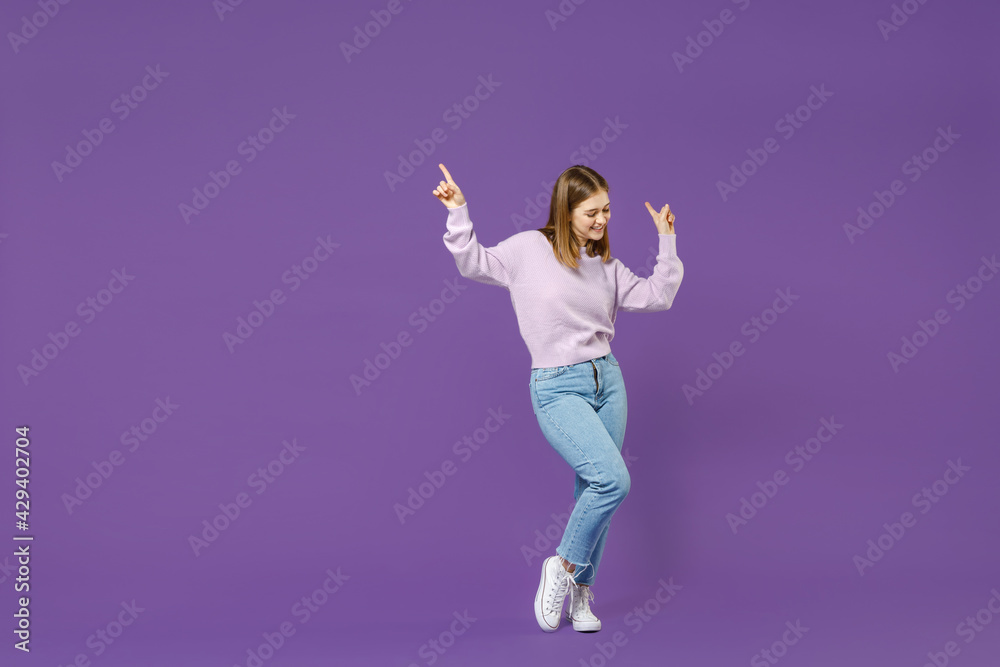 Full length young overjoyed excited joyful smiling happy student caucasian woman in purple sweater dancing point finger up with isolated on violet background studio portrait People lifestyle concept.