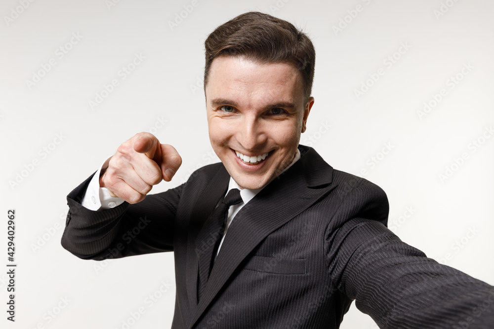 Close up young employee business corporate lawyer man in classic formal black grey suit shirt tie work in office do selfie shot mobile phone point finger camera isolated on white background studio Close up young employee business corporate lawyer man in classic formal black grey suit shirt tie work in office do selfie shot mobile phone point finger camera isolated on white background studio