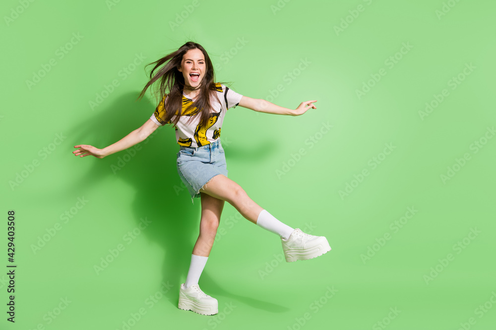 Full length photo of happy cheerful young positive woman dance raise hands isolated on green color background