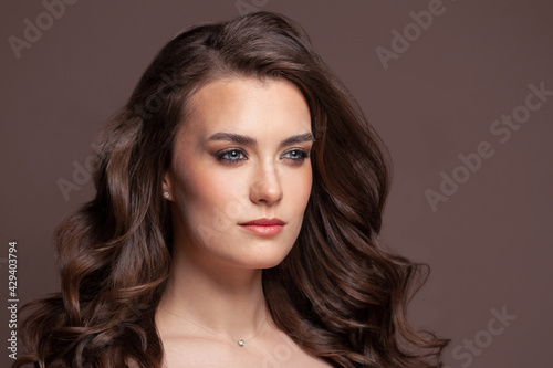 Perfect brunette woman with brown curly hairstyle on brown background