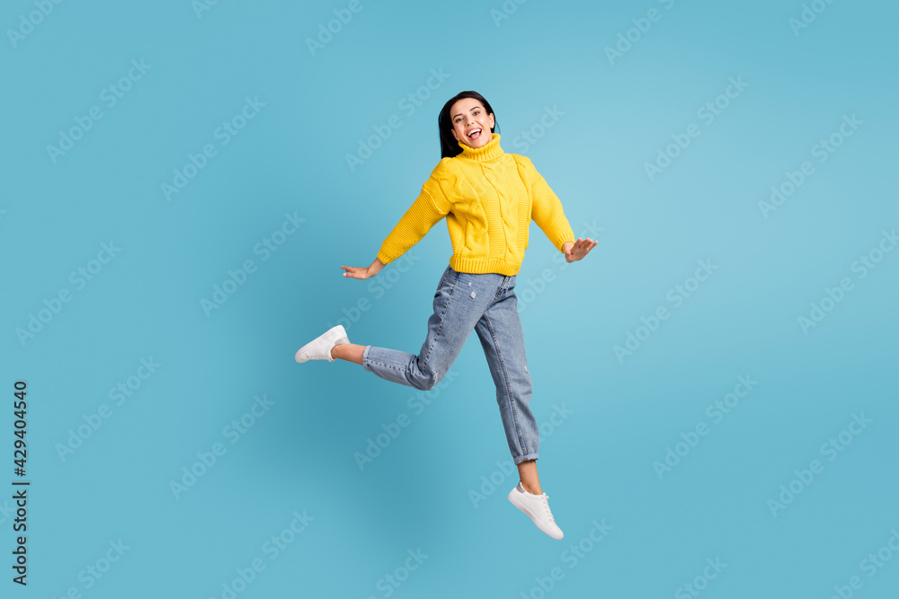 Full length body size side photo of brunette jumping high laughing overjoyed isolated on vibrant blue color background