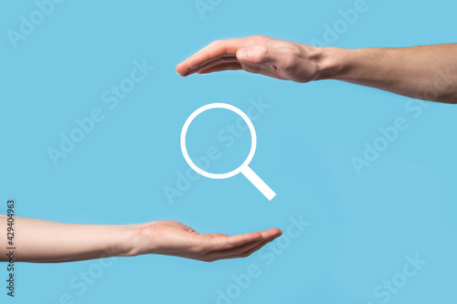Male hand holding magnifying glass ,search icon on blue background. Concept search engine optimization, customer support.Browsing Internet Data Information.Networking Concept.