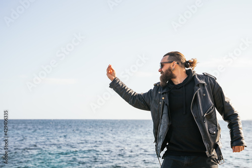 Caucasian Italian man with long hair and beard angry with the sea making the La Pigna gesture with his hand at sunset. Palma de Mallorca, Spain (Copyspace)