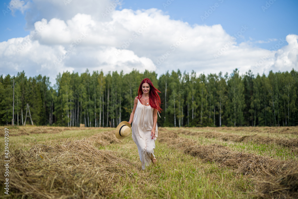 young woman with long red flowing hair in a white dress runs across the field young woman with long red flowing hair in a white dress runs across the field