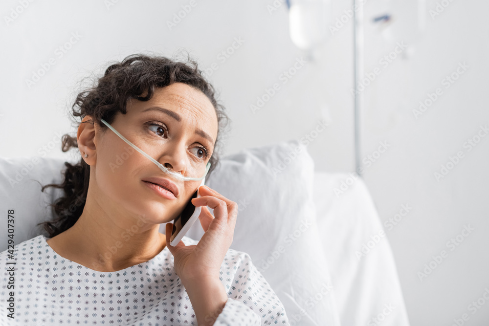upset african american woman looking away while talking on mobile phone in clinic upset african american woman looking away while talking on mobile phone in clinic