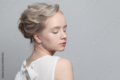 Pretty blonde woman with updo hairstyle on white background