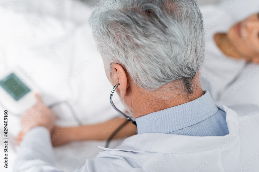 Obraz premium overhead view of mature doctor measuring blood pressure of ill african american woman