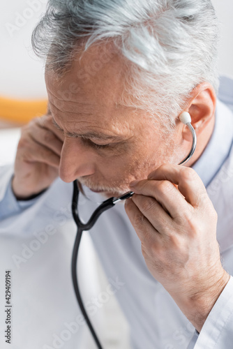 high angle view of mature doctor adjusting stethoscope in hospital
