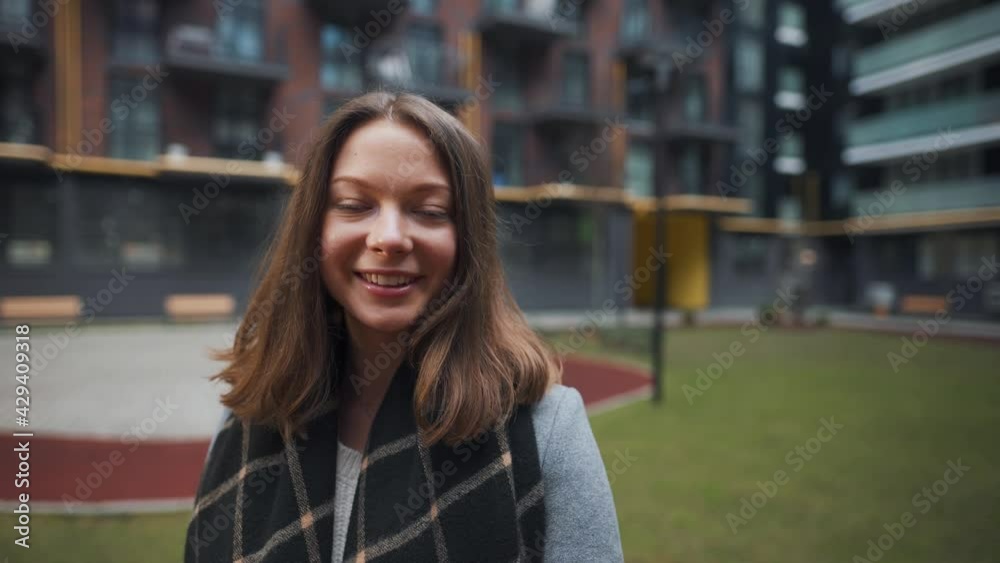 Portrait of a gorgeous dark haired woman smiling charmingly while standing against the background of modern buildings. Happy young woman enjoys life. Portrait of a gorgeous dark haired woman smiling charmingly while standing against the background of modern buildings. Happy young woman enjoys life.