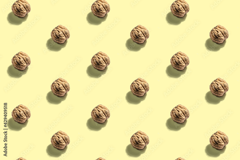 The whole unpeeled walnuts pattern on yellow background The whole unpeeled walnuts pattern on yellow background