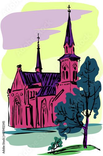 Catholic temple in the Gothic style against the sky and with a tree in the foreground.