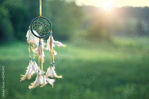 magic dream catcher on summer landscape, gentle green natural background. ethnic ritual, Shaman native amulet. hygge, lagom, relax concept. copy space