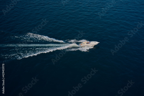 Modern boat with the flag of Germany on turquoise water. Large speed boat moving at high speed side view. Travel - image. Drone view of a boat the blue clear waters.