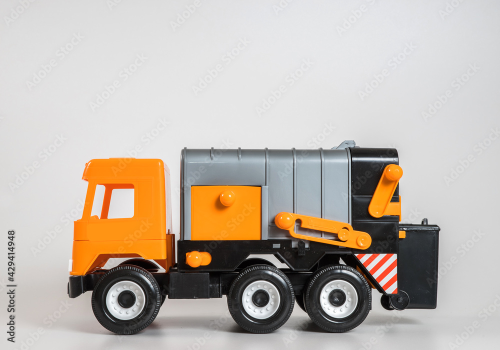 Multi-colored plastic children's toy cars on a white background. Orange garbage truck.