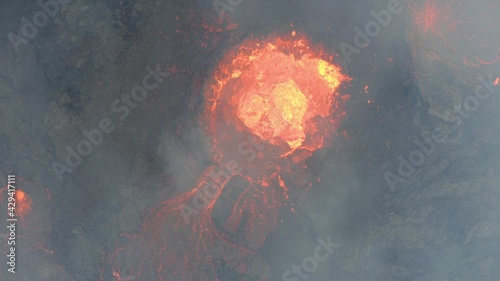 Aerial view over a splattering magma crater in the earth surface - top down, drone shot photo