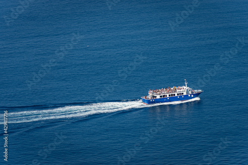 Aerial view of a blue ferry boat with many tourists on board, during sailing to the Cinque Terre in the Mediterranean Sea. Gulf of La Spezia, Liguria, Italy, Europe. © Alberto Masnovo