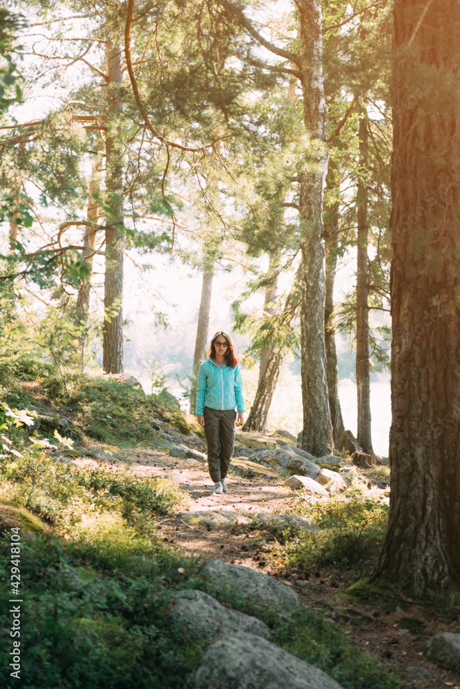 A woman traveler is walking along a forest path. The model goes straight to the camera.