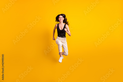 Full length body size photo of woman jumping running fast on sale smiling isolated bright yellow color background